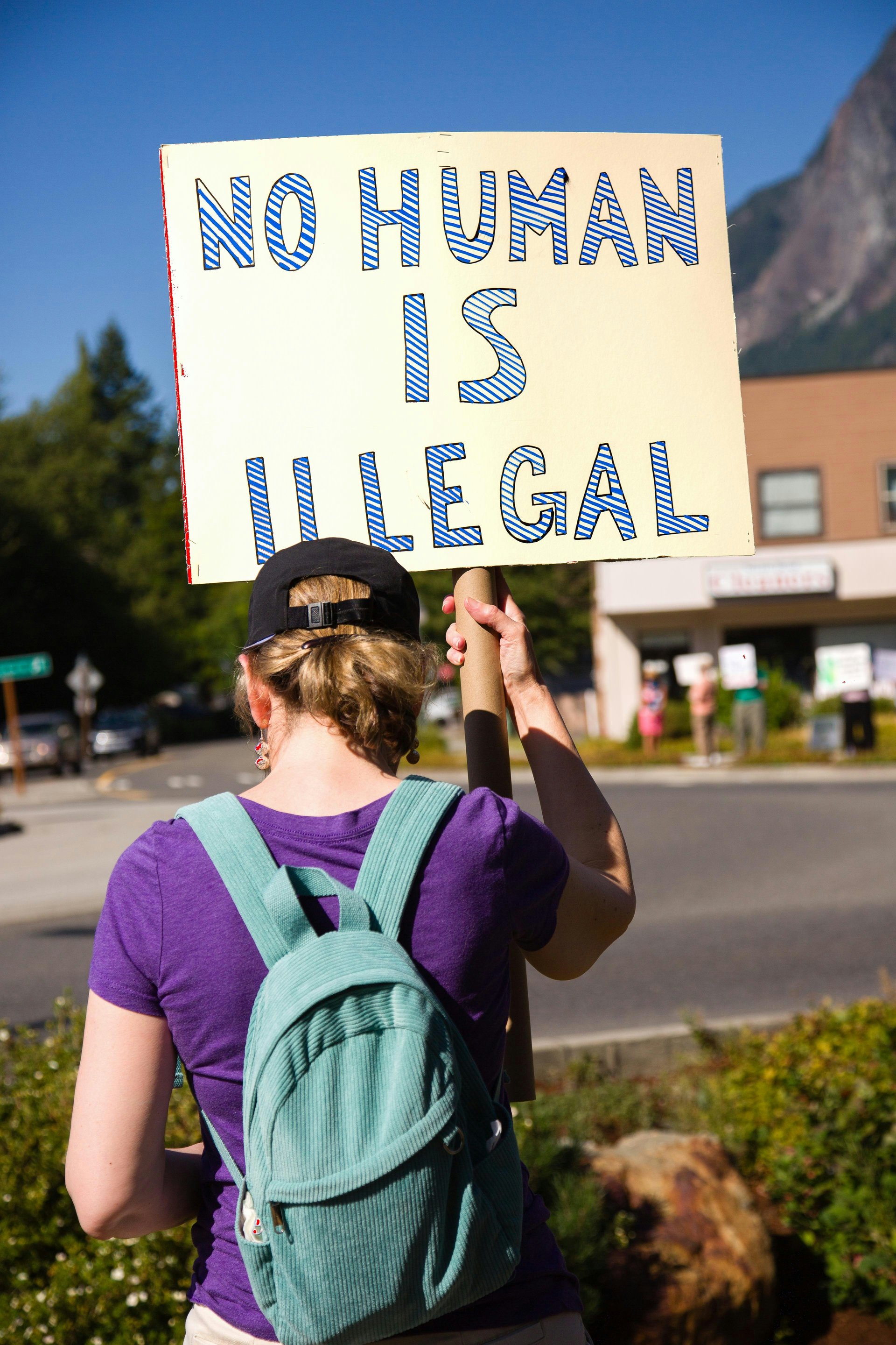 Person holding a sign reading No Human Is Illegal