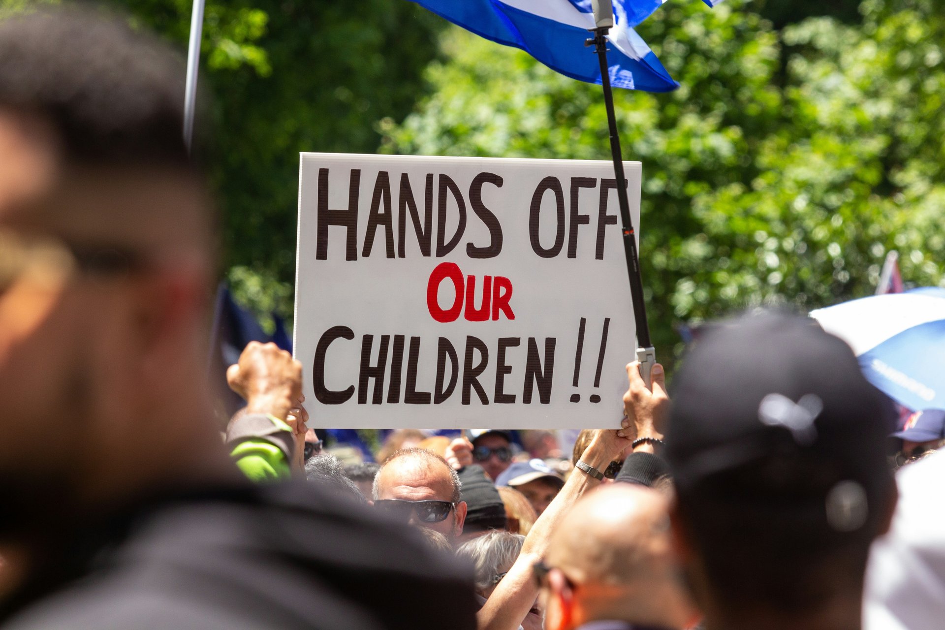 Protest with a sign reading 'Hands Off Our Children'